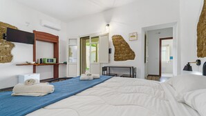 A hotel room with a large bed, a flat-screen TV, a microwave, and a stone accent wall.