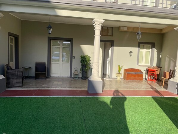 Un espace extérieur abrité comprenant un banc, une plante en pot, une table en bois et une porte.
