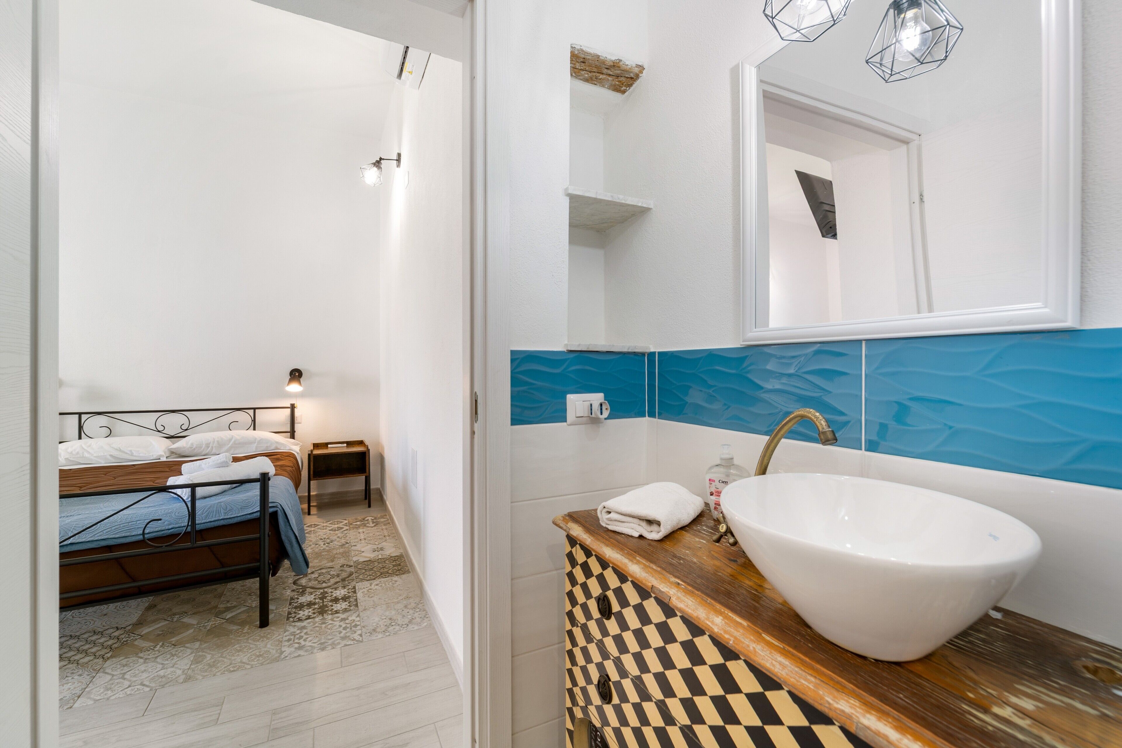 Un baño con un lavamanos grande blanco, un espejo y un tocador de madera con estampado de cuadros.