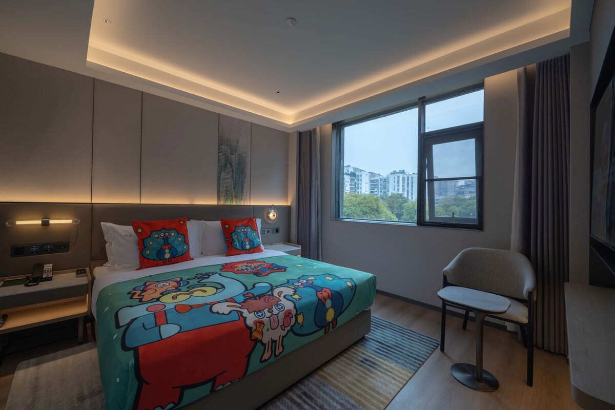 A modern hotel room with a large bed, a desk, and a chair.