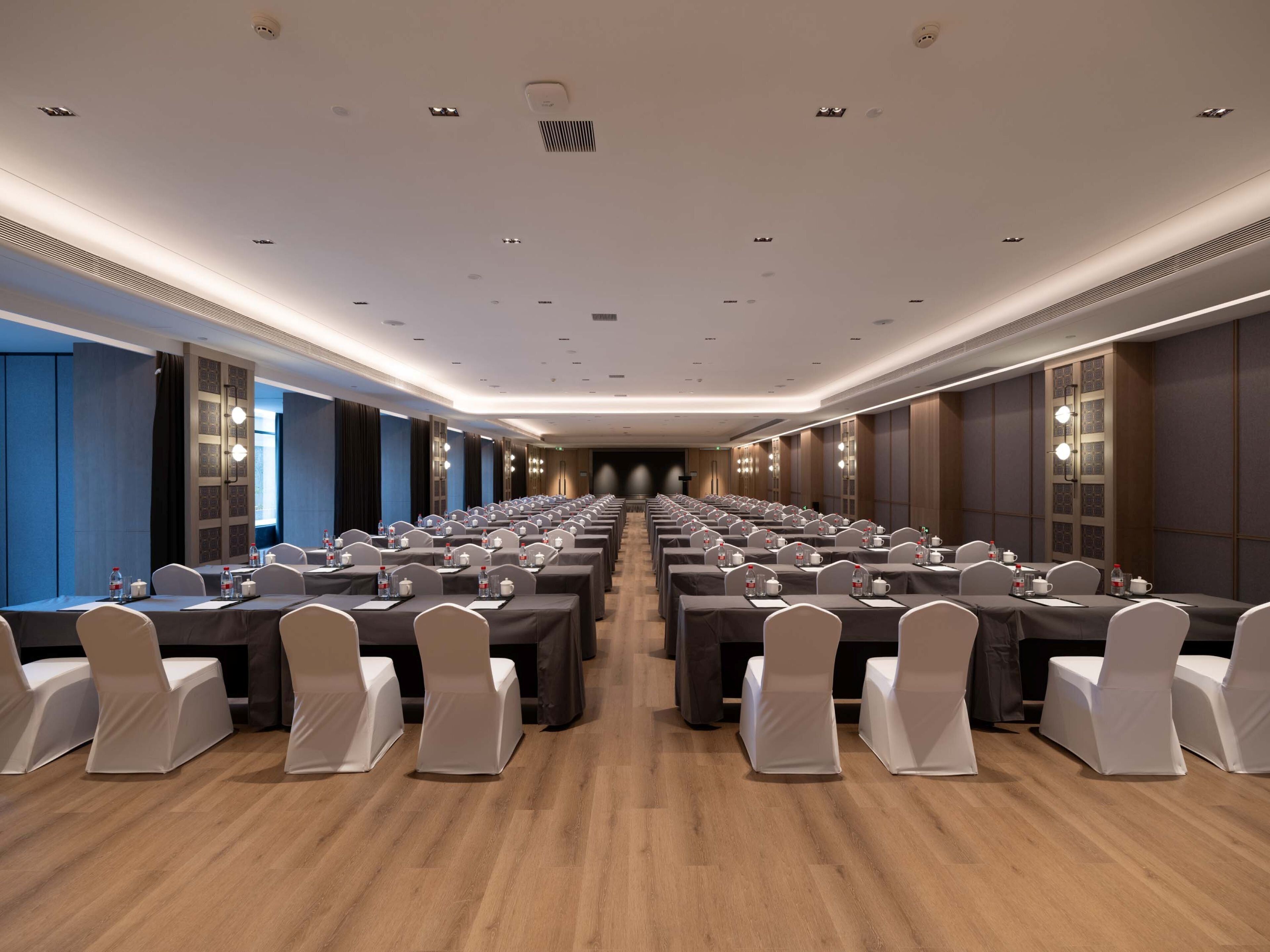 A conference room with rows of tables and chairs, equipped with water bottles and nameplates.
