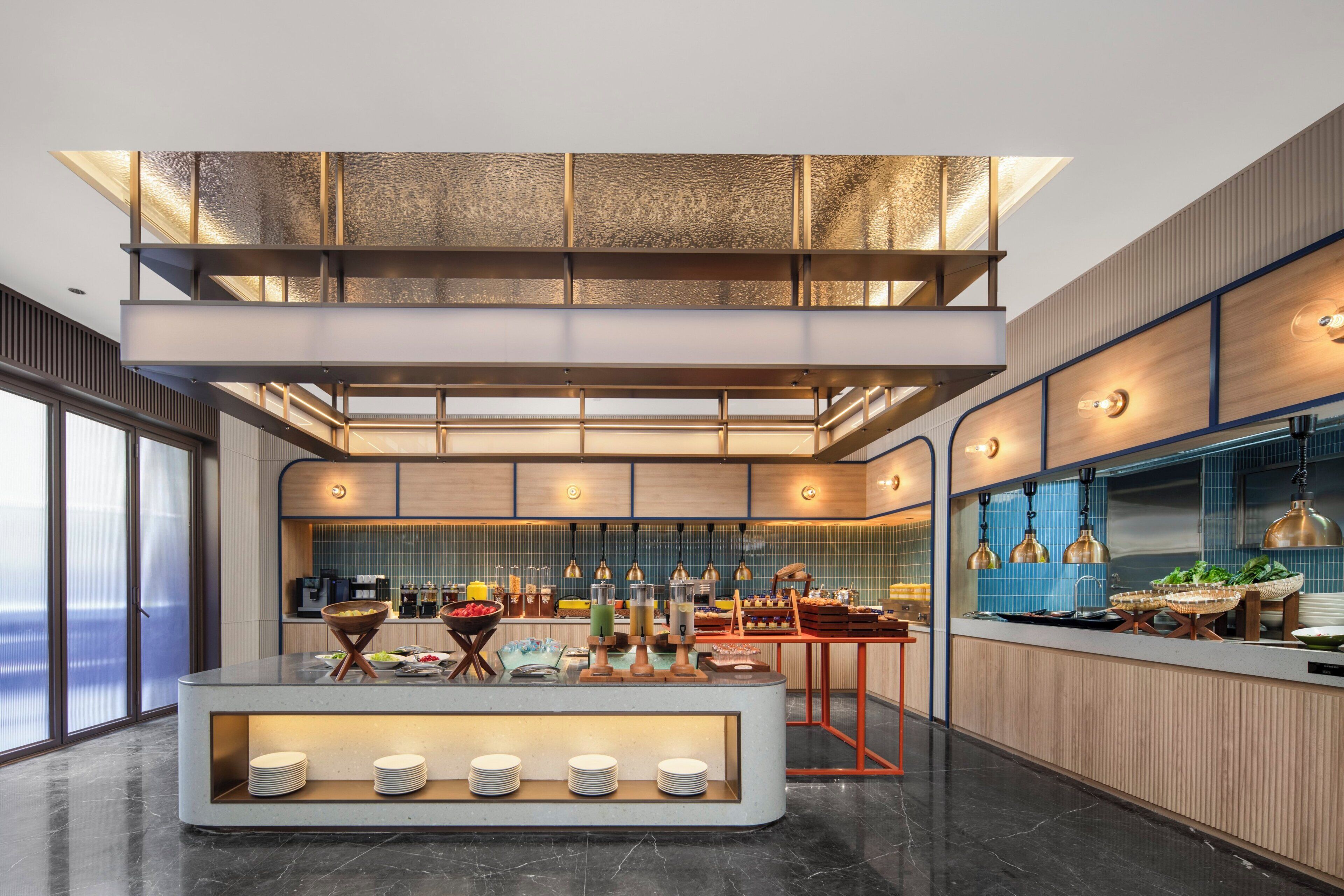 A modern kitchen with a buffet setup, a mezzanine level, and a view of the sea.