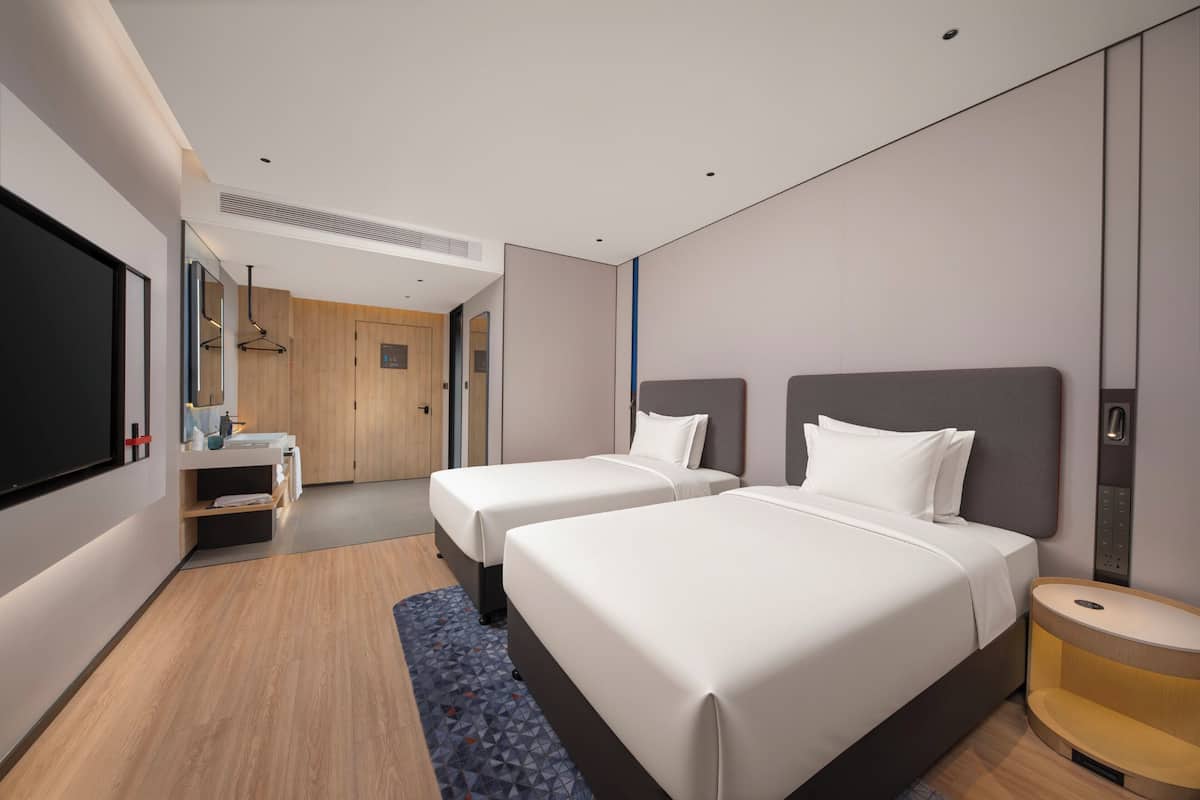 Une chambre d’hôtel avec deux lits, une télévision, un bureau et une salle de bain.