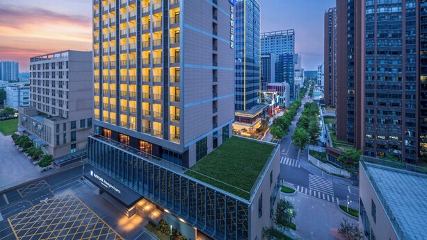 Een modern hotel met een glazen gevel, meerdere verdiepingen en een dakbostuin.