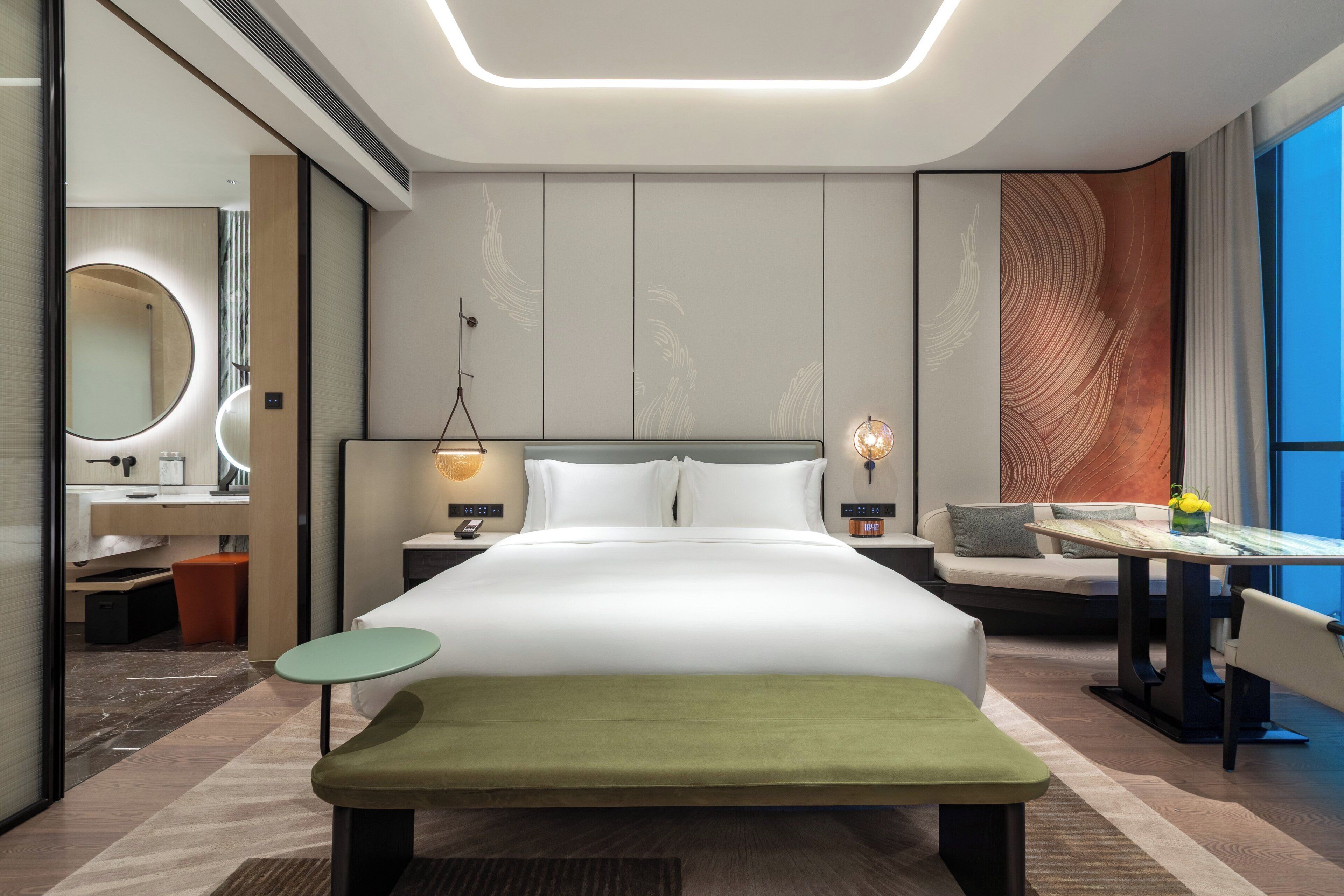 Een moderne hotelkamer met een groot bed, nachtkastjes, een bureau en uitzicht op de omgeving.