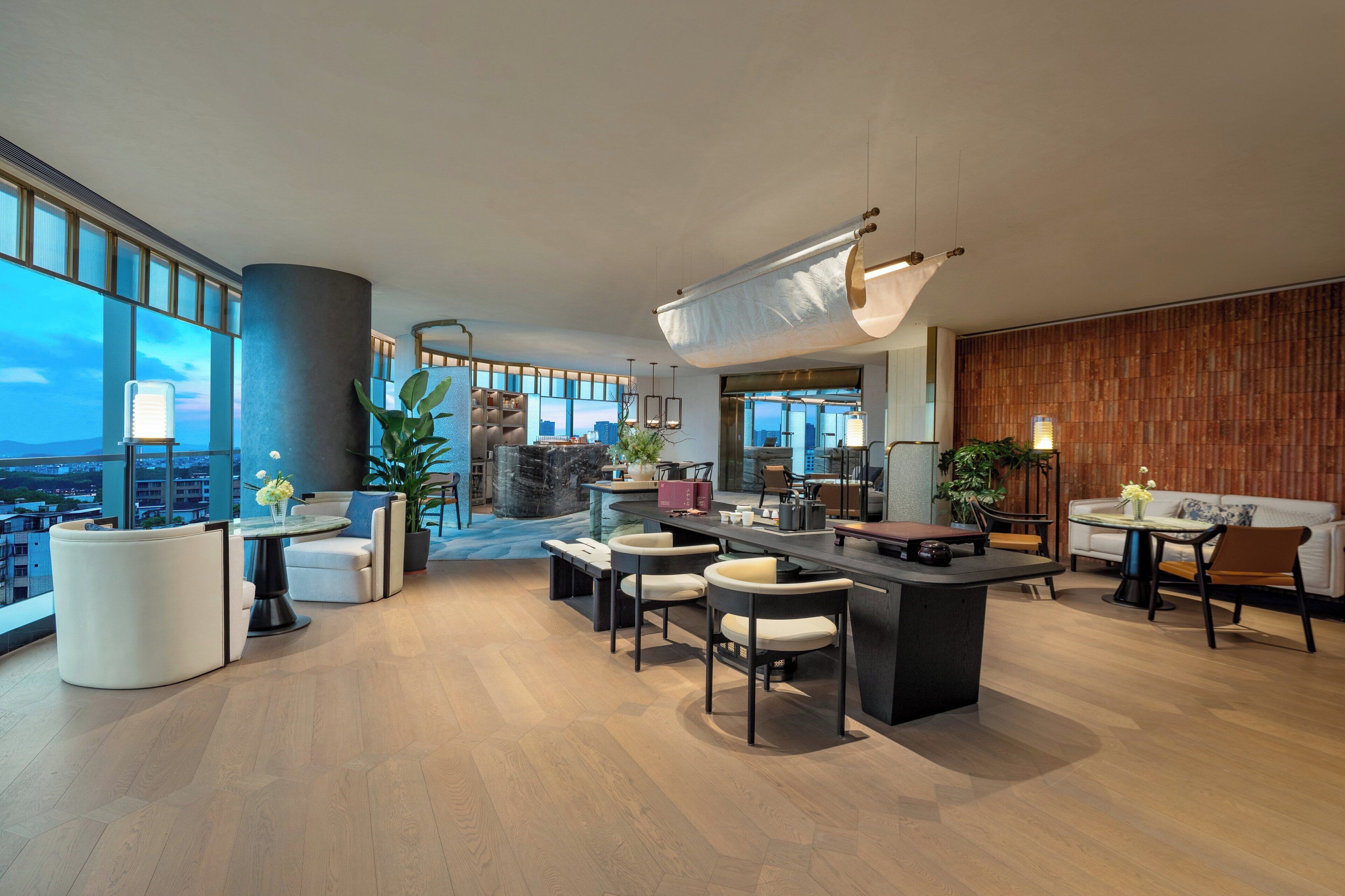 A modern interior with a bar area, seating, and large windows offering city views.