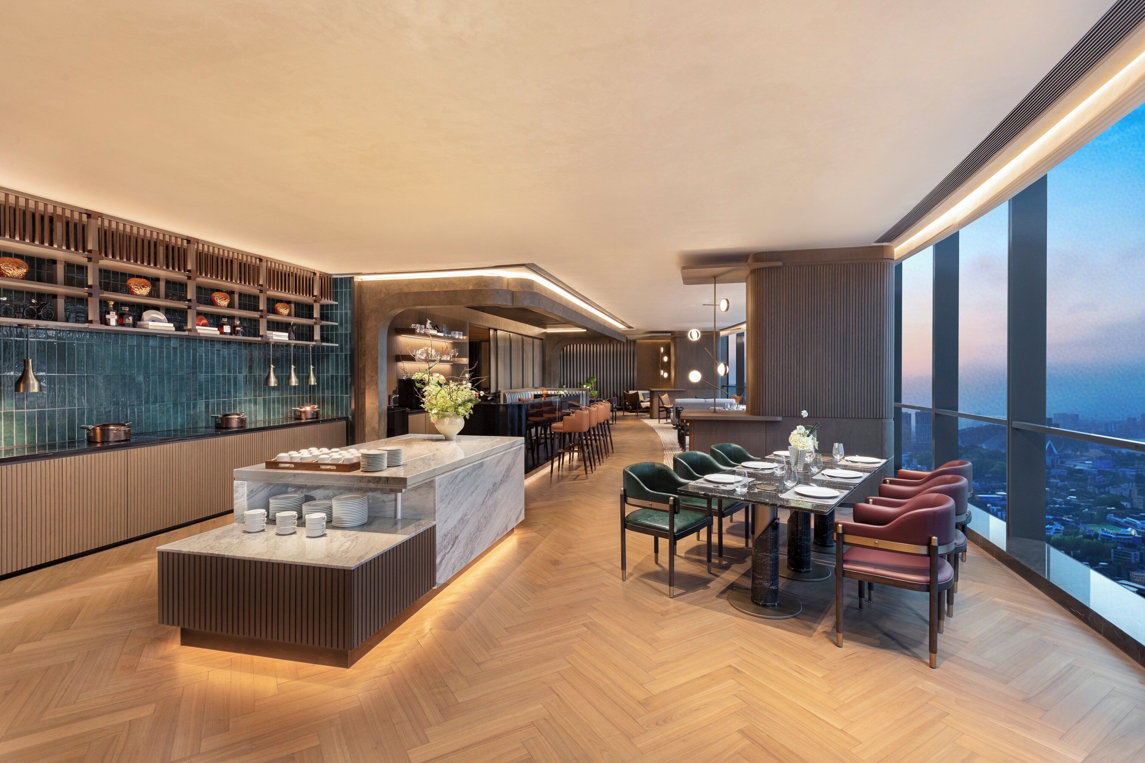 A modern hotel lobby with a central island, seating area, and a view of the city.