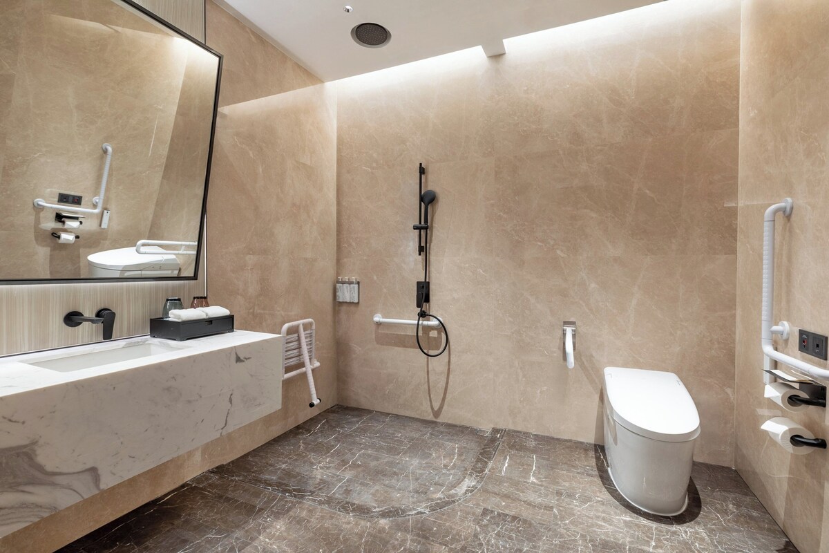 A modern bathroom with a large mirror, a sink, a toilet, and a shower area.