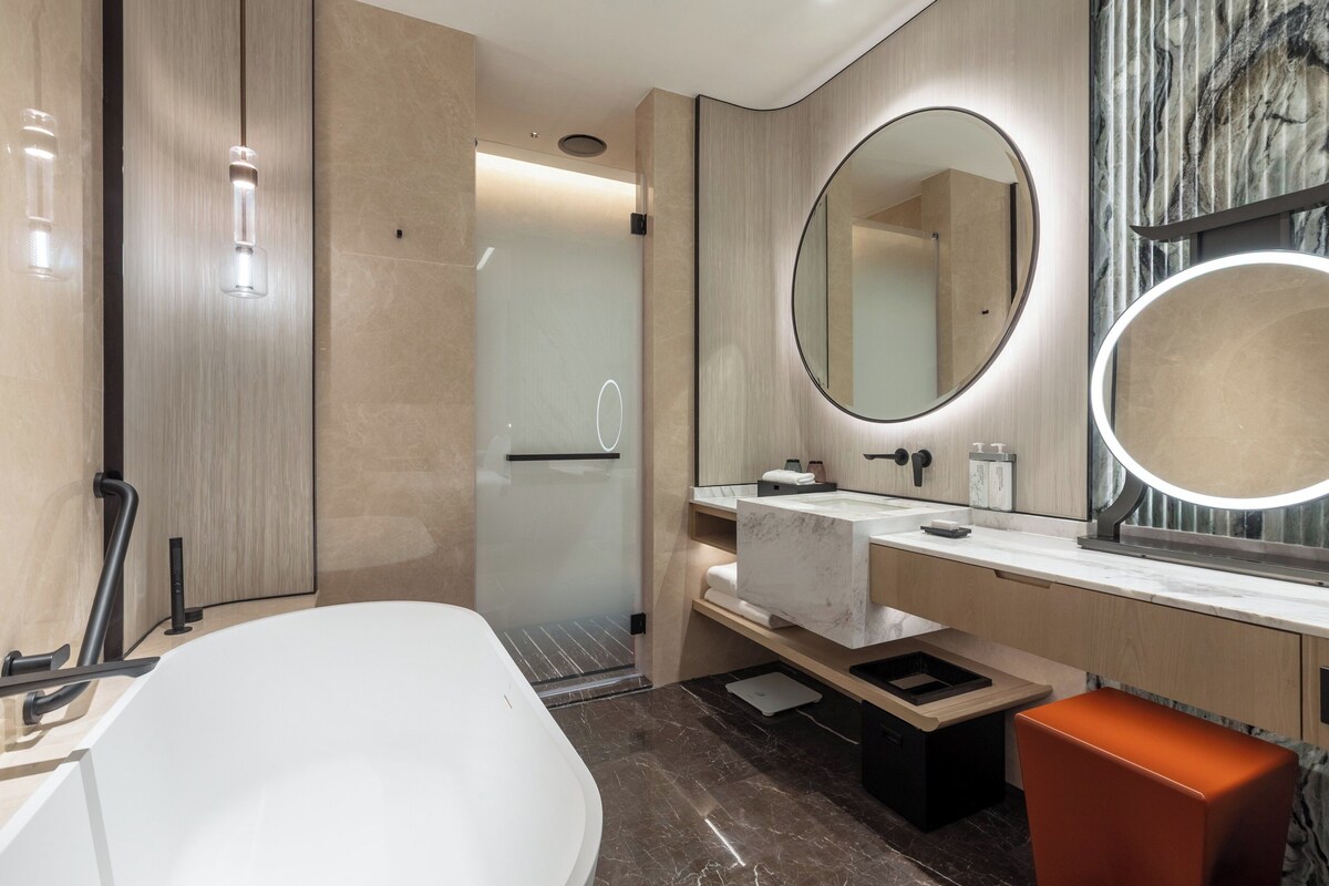 A modern bathroom with a large bathtub, a vanity with a mirror, and a shower area.