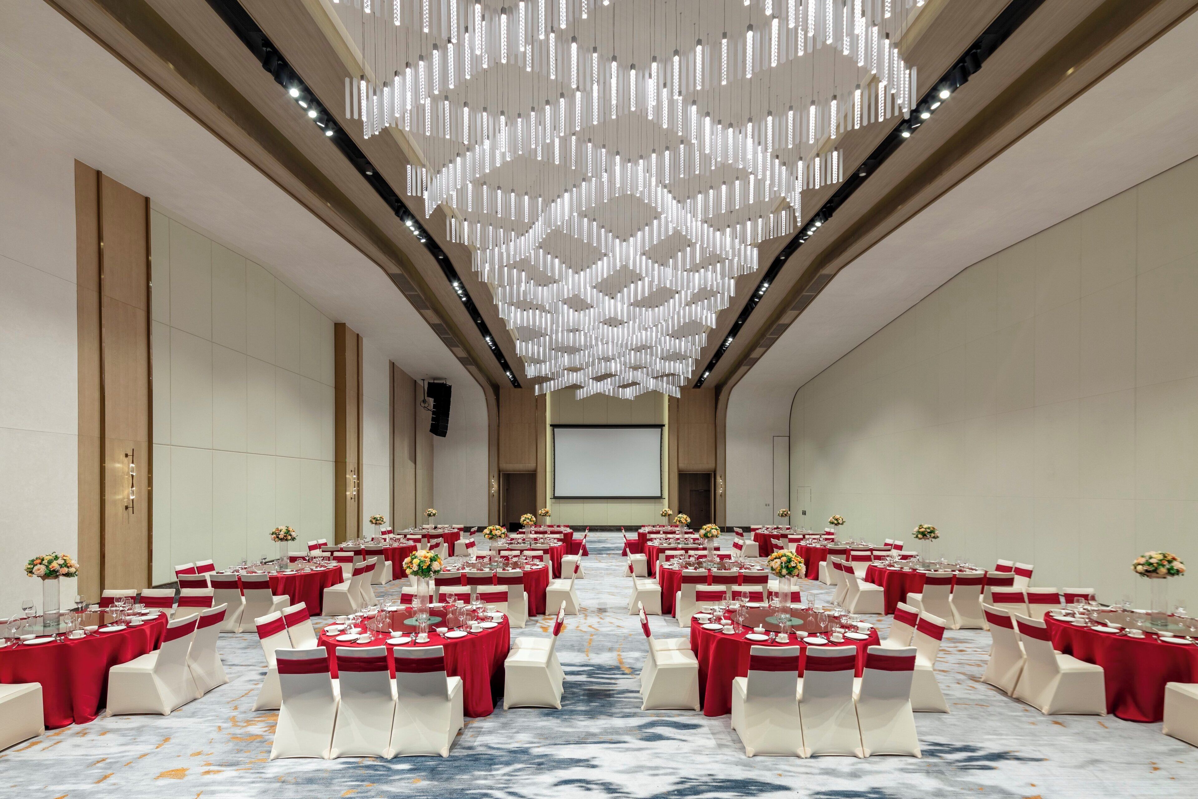 Une salle de conférence avec des rangées de tables, des chaises et un grand écran à l’avant.