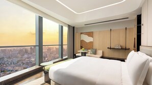 Una habitación de hotel moderna con una cama grande, un espacio de descanso pequeño y vistas a la ciudad.