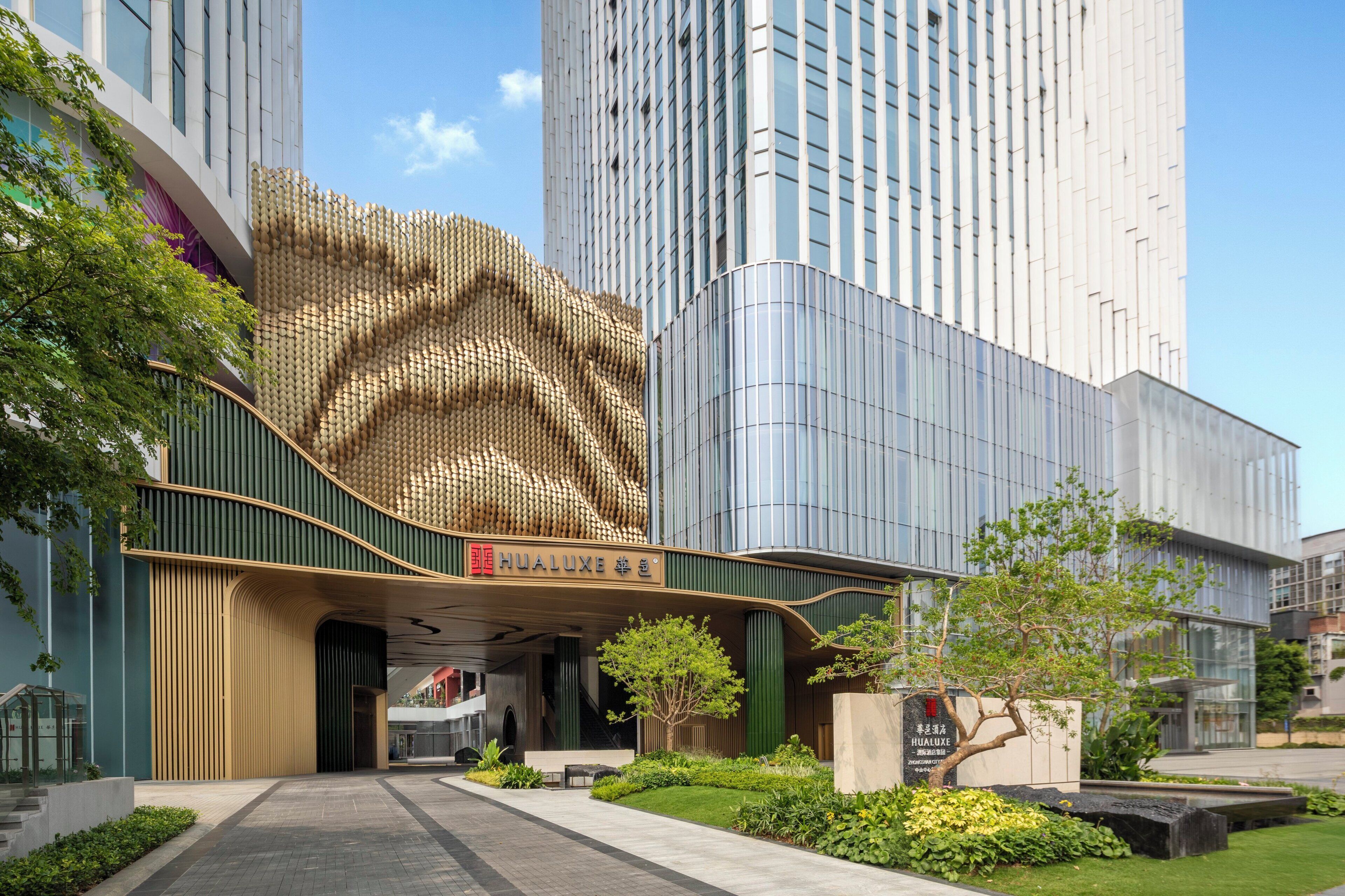 A modern building with a unique textured facade, a prominent entrance, and a well-maintained garden area.