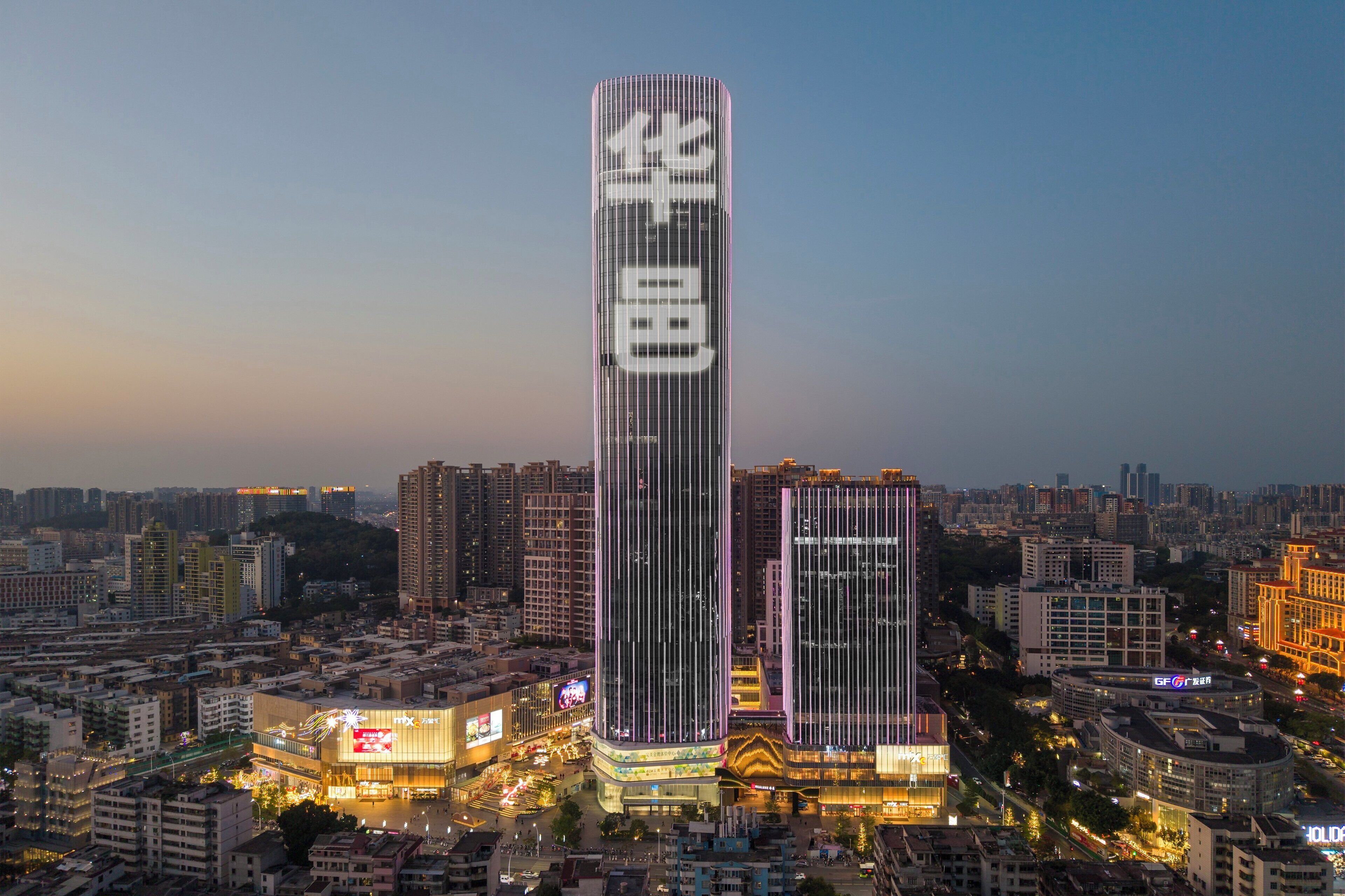 A high-rise building with a prominent vertical design, surrounded by a dense urban environment.