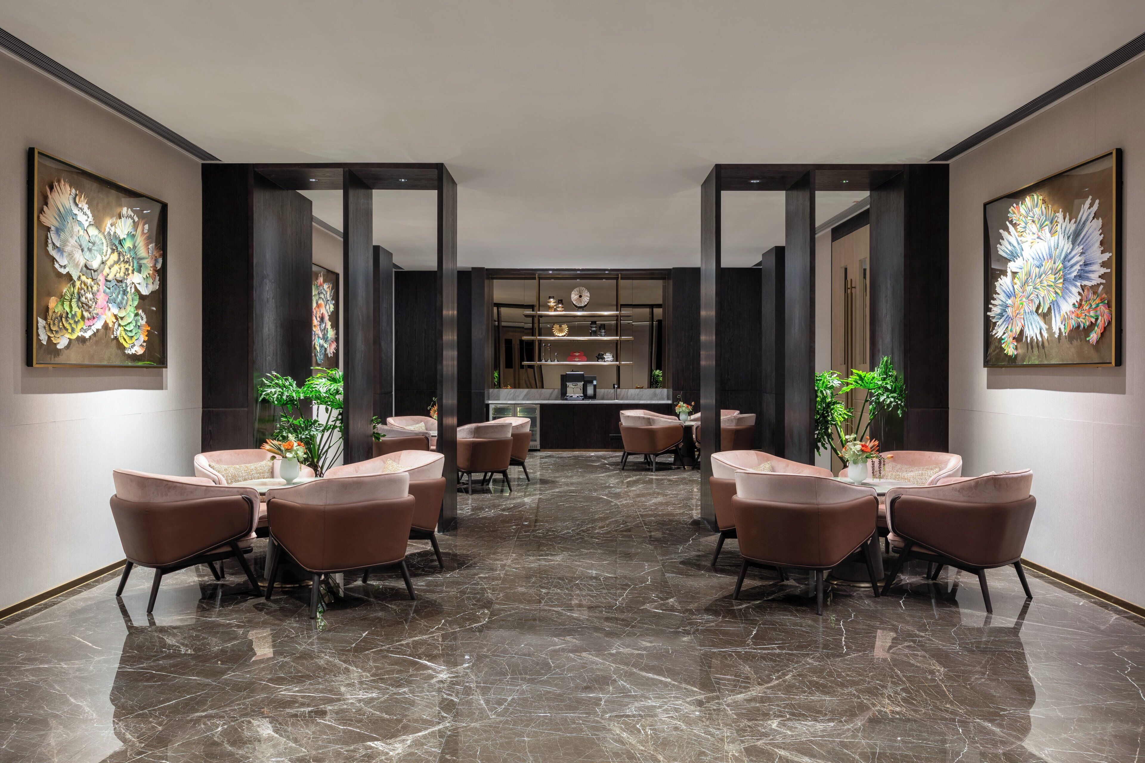 A hotel lobby with a marble floor, brown leather chairs, a reception desk, and large abstract paintings on the walls.