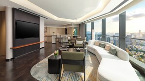 Una sala de estar moderna con un televisor de pantalla plana grande, un sofá, una mesa de centro y vistas a la ciudad.