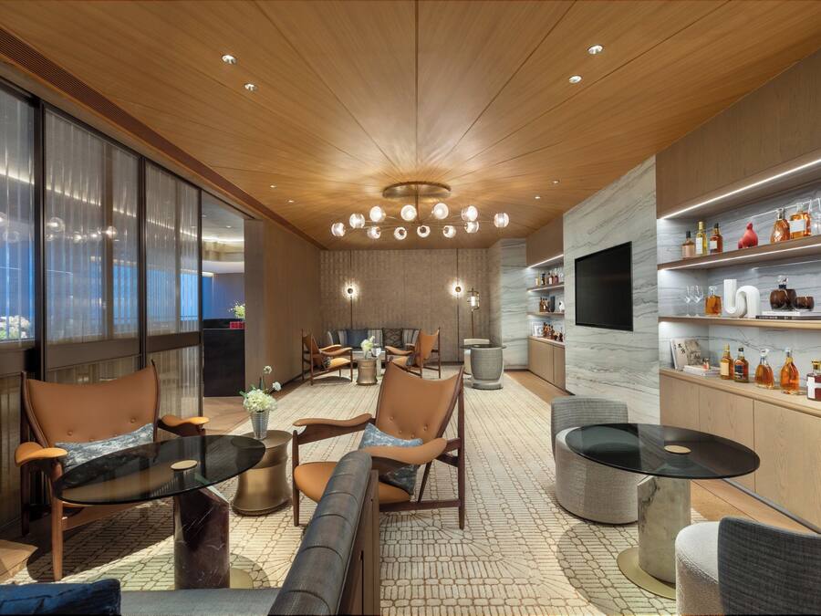 Ein modernes Interieur mit Holzbalkendecke, einer Sitzecke und einer Bar mit Flaschenregalen.