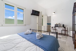 Une chambre à coucher avec un lit, un téléviseur fixé au mur et un bureau avec une chaise.
