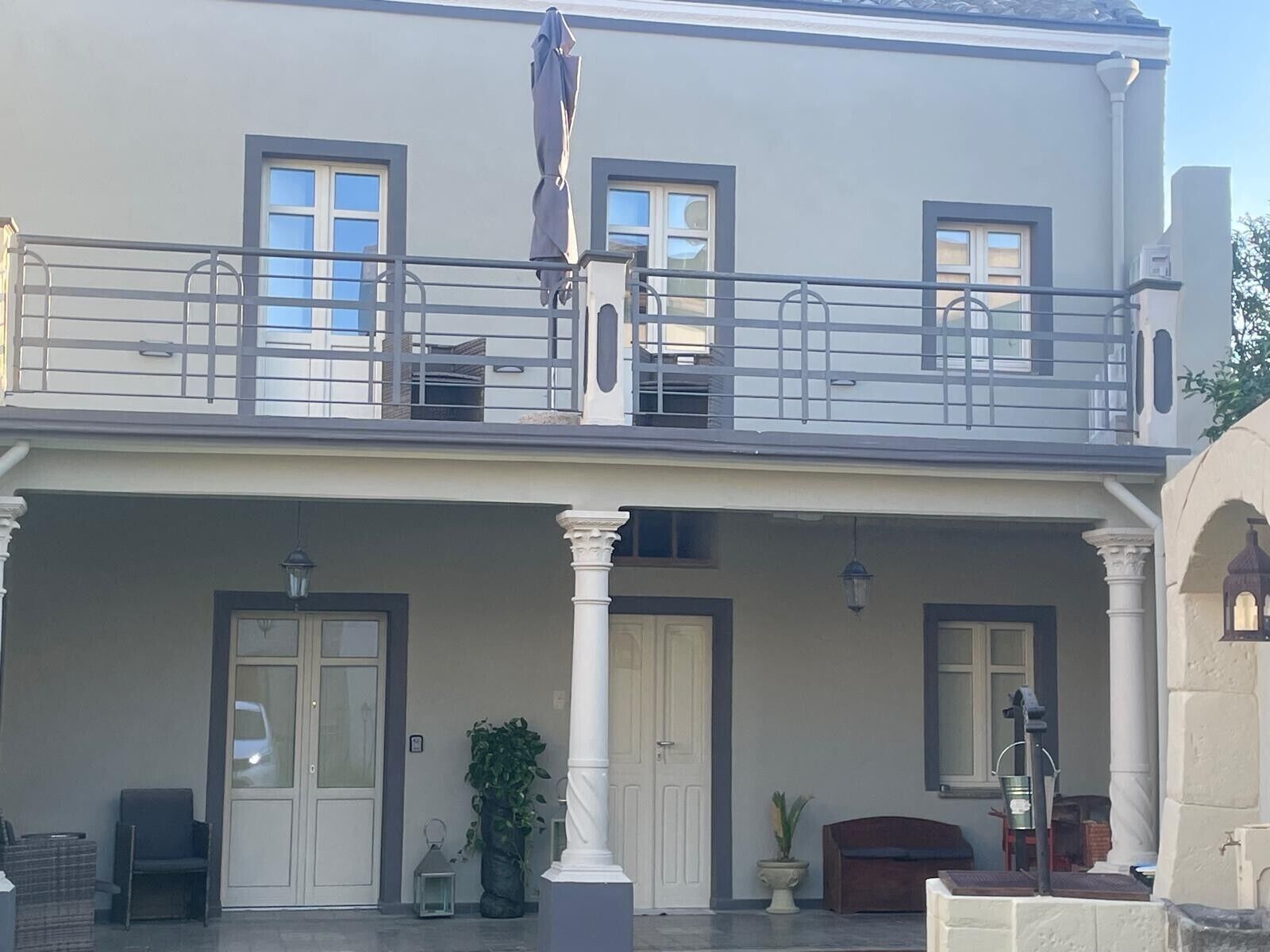 Um edifício de dois andares com varanda, janelas amplas e varanda frontal coberta com colunas.