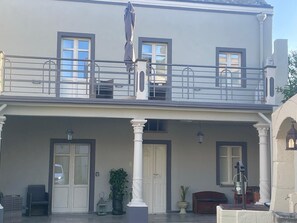 A two-story building with a balcony, large windows, and a covered front porch with columns. - Room 6 – Double Room with Garden View (Assemini)