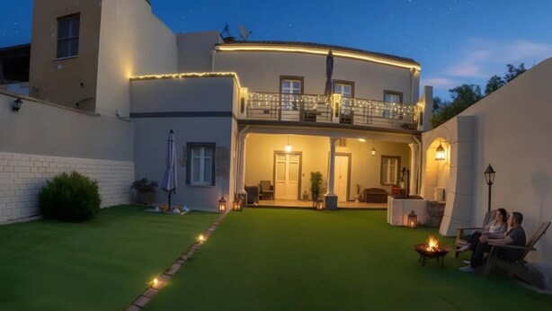Uma casa moderna com um gramado bem cuidado, uma varanda iluminada e uma área com lareira.