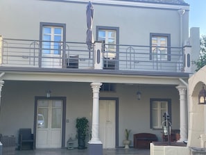 En toetagers bygning med balkon, store vinduer og en overdækket veranda med søjler.