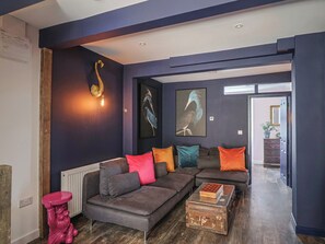 Un salon moderne avec un canapé d’angle, une table basse et des œuvres d’art accrochées aux murs.
