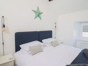 A bedroom with a bed, two bedside tables, a star decoration, and two wall-mounted lamps. - Avocet (Lyme Regis)
