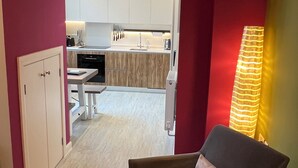 A compact living space with a kitchenette, a dining area, and a seating area with a chair and a table. - Boutique Style 2 bed Maisonette (Watlington)