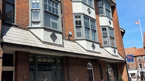 A two-story building with a corner entrance, large windows, and a small porch area. - Boutique Style 2 bed Maisonette (Watlington)