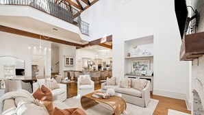A spacious living area with a high ceiling, a fireplace, and a kitchen in the background. - Close to Communal Pool with LSV (Santa Rosa Beach)