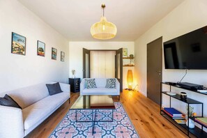 A modern living room with a sofa, a glass coffee table, a patterned rug, a television, and a bookshelf. - Apartment "Saint-Rémy" (Saint-Rémy-de-Provence)