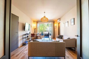 A modern living room with a sofa, armchairs, a coffee table, a TV, and a balcony with a view. - Apartment "Saint-Rémy" (Saint-Rémy-de-Provence)