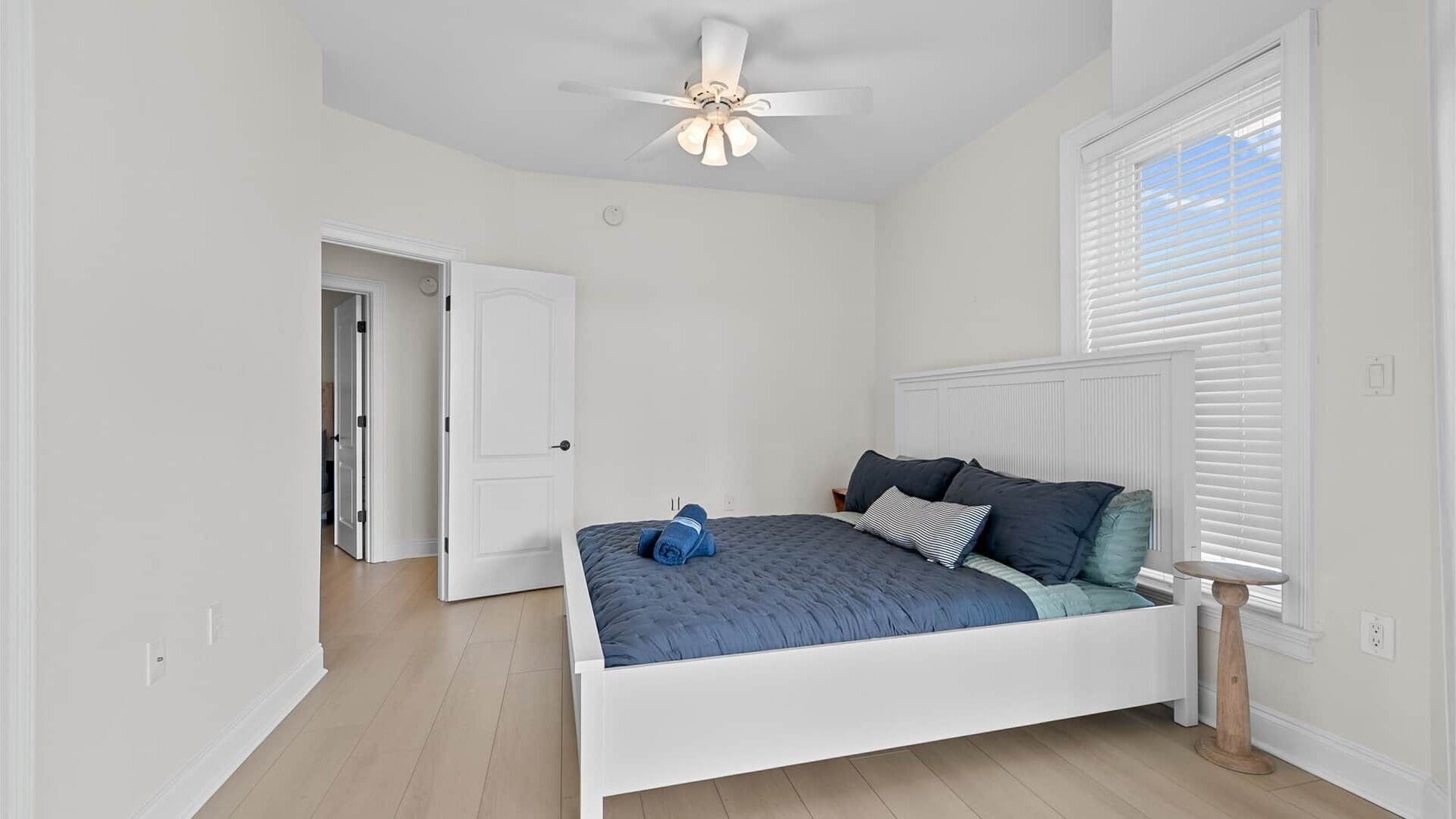 Camera da letto con un letto, una ventola a soffitto, una finestra con persiane e una porta che conduce a un'altra stanza.