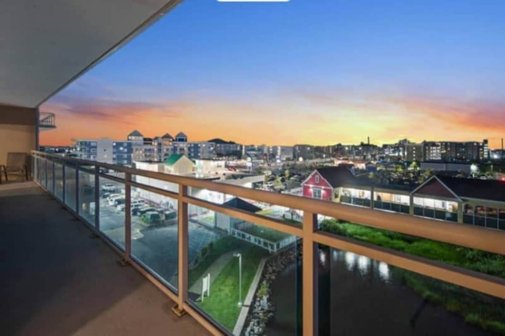 A balcony with a view of a cityscape at sunset.
