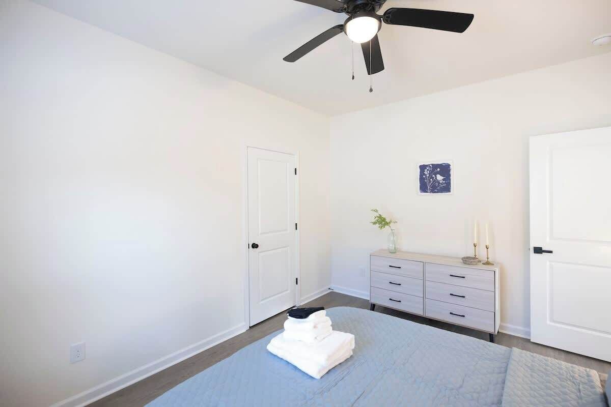 Une chambre à coucher avec un lit, un ventilateur de plafond, une commode et une porte.