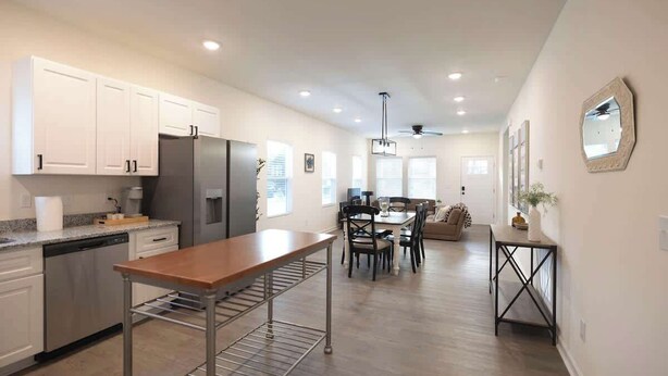 A modern kitchen with white cabinets, a stainless steel refrigerator, and a wooden table. - 5 Min to Elon | 7 Min to Downtown | Washer + Dryer (Burlington)