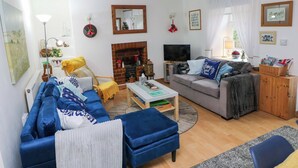 Un salon comprenant un canapé, un fauteuil, une table basse, une cheminée, un téléviseur et divers éléments de décoration.