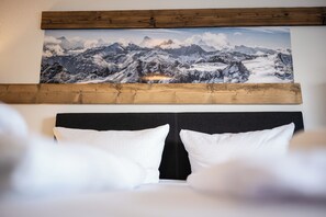 A bedroom with a mountain landscape painting above the bed, a black headboard, and white pillows. - Mountaineer sleeping places | Parking & Wifi (Kempten (Allgäu))