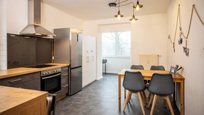Een moderne keuken met roestvrijstalen apparatuur, een houten aanrecht en een eethoek met een tafel en stoelen.