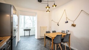 Een moderne keuken met een houten eettafel, zwarte stoelen en een koelkast.