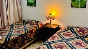 Una camera con due letti, un comodino con una lampada e due quadri appesi al muro.