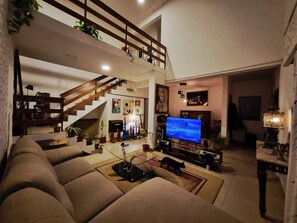 Un salon spacieux avec une grande télévision, un escalier et un coin salon confortable.