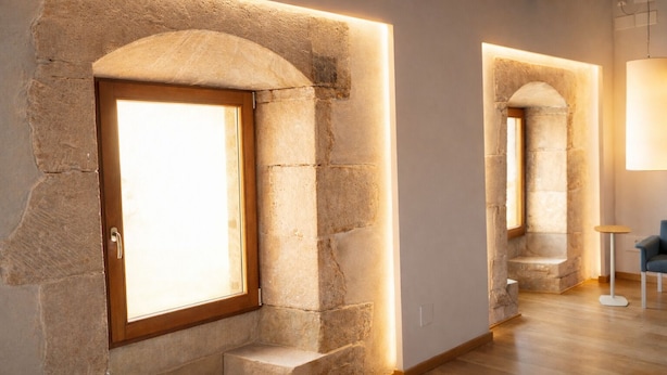 A modern interior with stone arches, a wooden door, and a small seating area. - Hotel Santuari Balaguer (Balaguer)