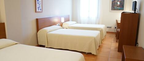 Habitación de hotel con dos camas, un escritorio, una silla, un televisor y un cuadro en la pared.