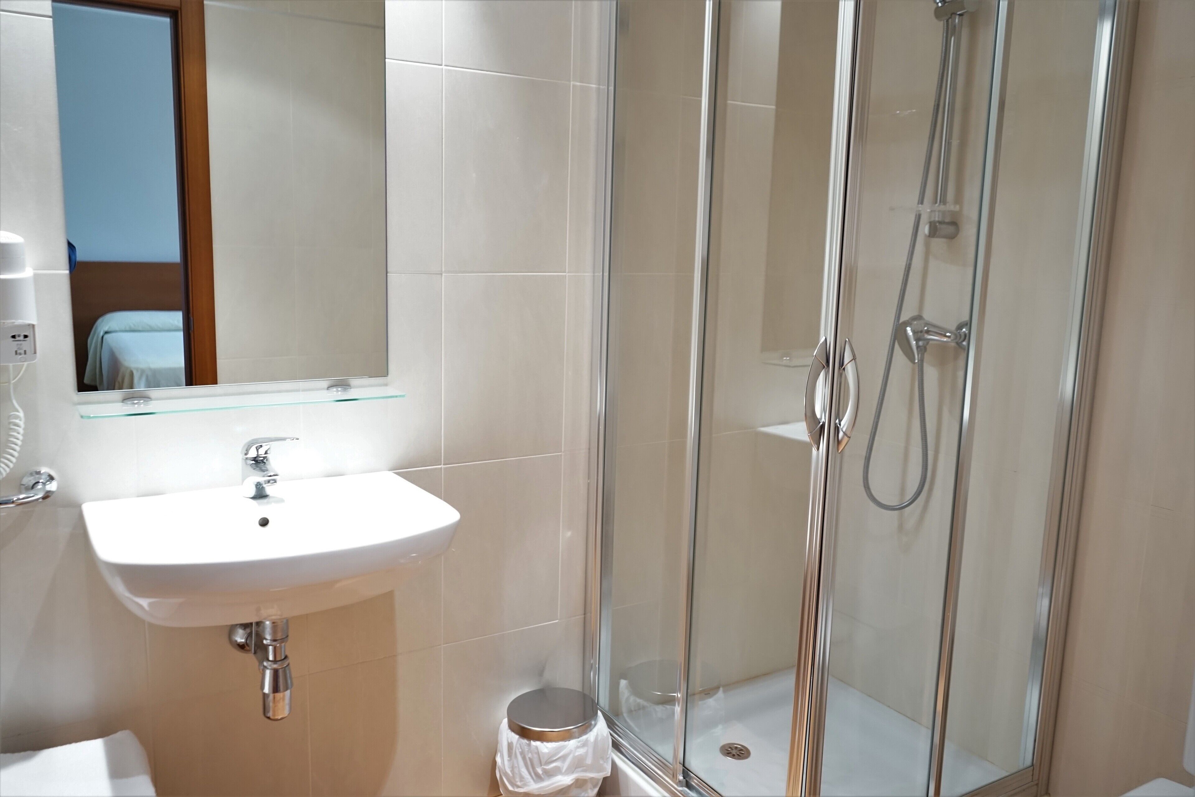 A modern bathroom with a glass-enclosed shower, a white sink, and a mirror above the sink.