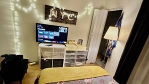 Una habitación de hotel con cama, televisor y espacios de almacenamiento.