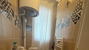 Un baño estrecho con lavamanos, inodoro y zona de ducha.
