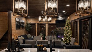 Een gezellige woonkamer met een open haard, een kerstboom en moderne verlichtingsarmaturen.
