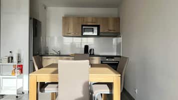 A modern kitchen with wooden cabinets, a microwave, and a dining area with a table and chairs.