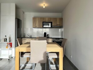 Una cocina moderna con armarios de madera, un microondas y un comedor con mesa y sillas.